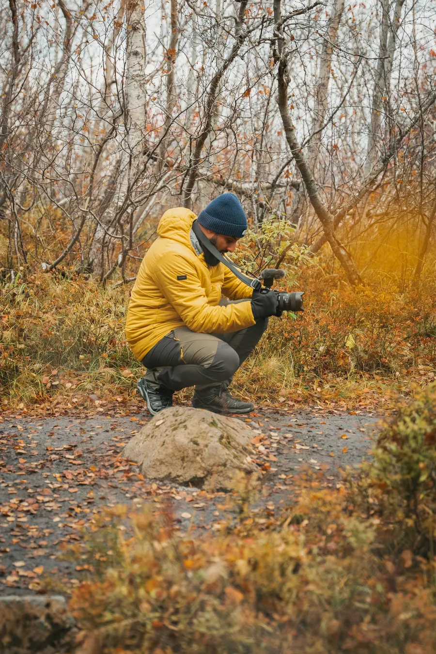 Hacomar crouching to film in an autumn forest