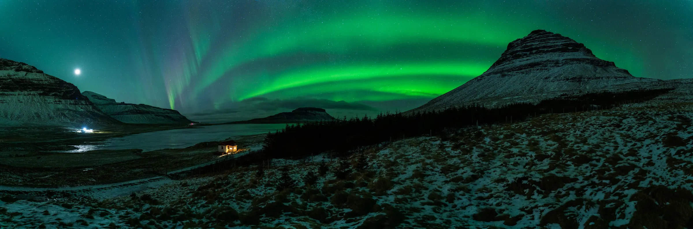 Vista panorámica de una aurora verde sobre montañas nevadas en Islandia